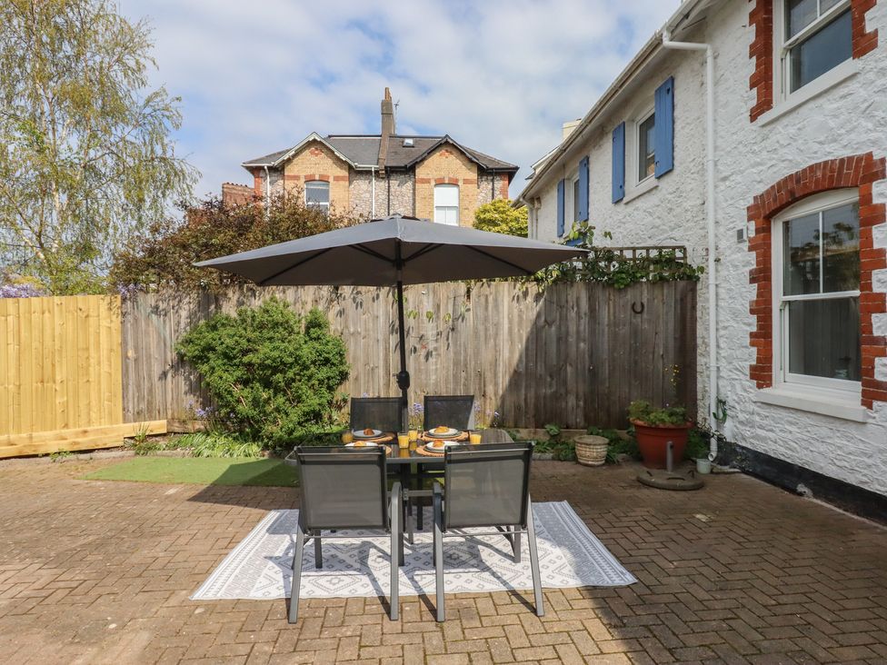 An outdoor dining area with a table and umbrella at Hares Cottage in Torquay