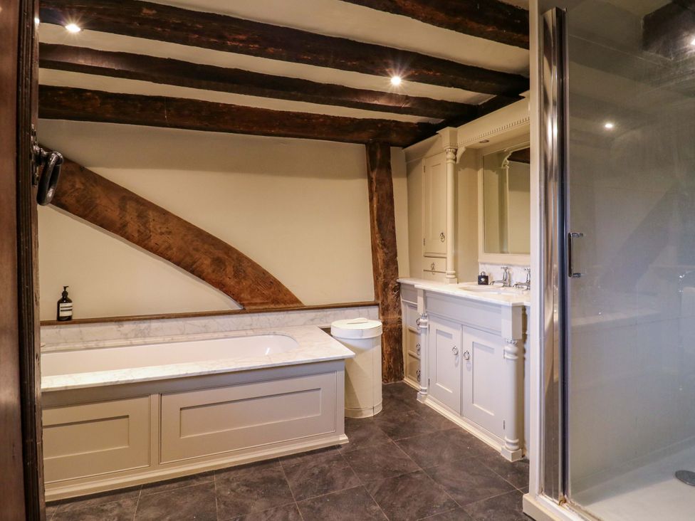 A bathroom with a bathtub, sink, shower, and wooden beams at Dukes Place