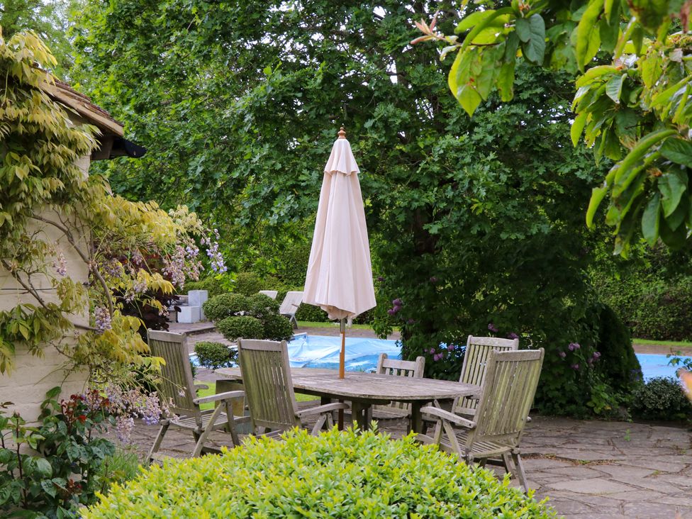 A garden with a table and chairs near a pool at Dukes Place
