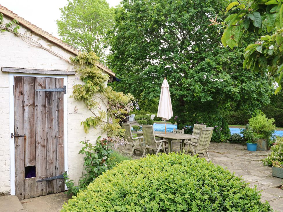 A garden with a shed, table and chairs under an umbrella at Dukes Place