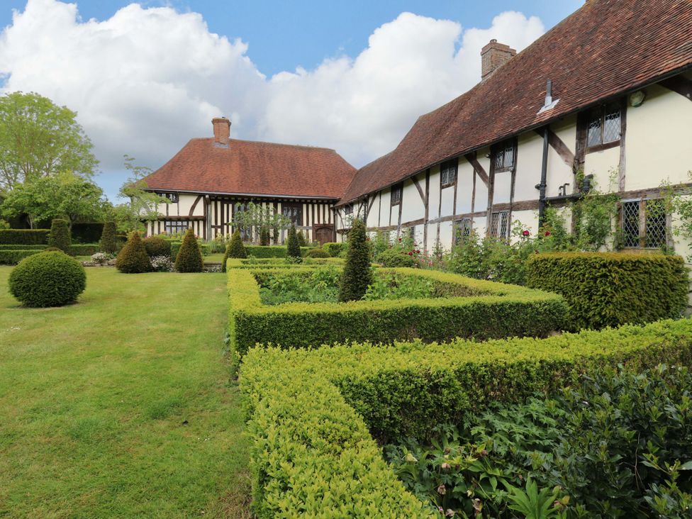 A garden with carefully shaped hedges and two houses at Dukes Place