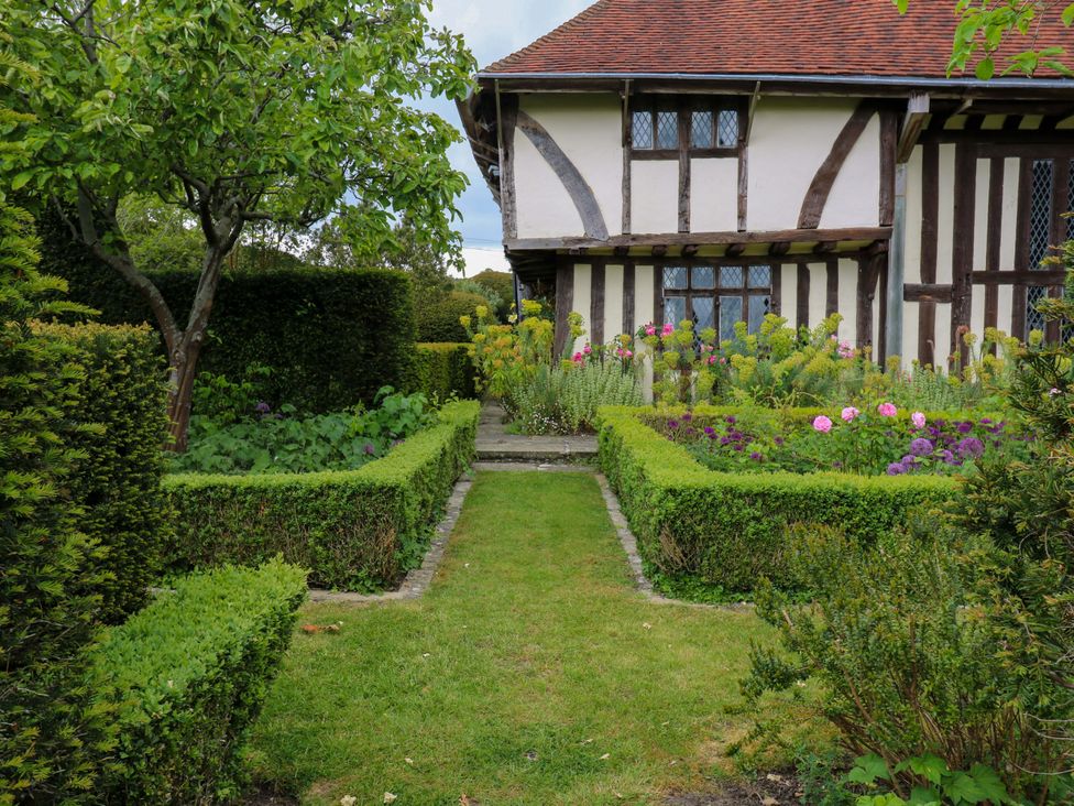 A garden with hedges and flowers beside a house at Dukes Place
