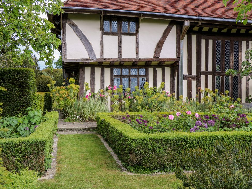 A garden with flowers and hedges next to a house at Dukes Place