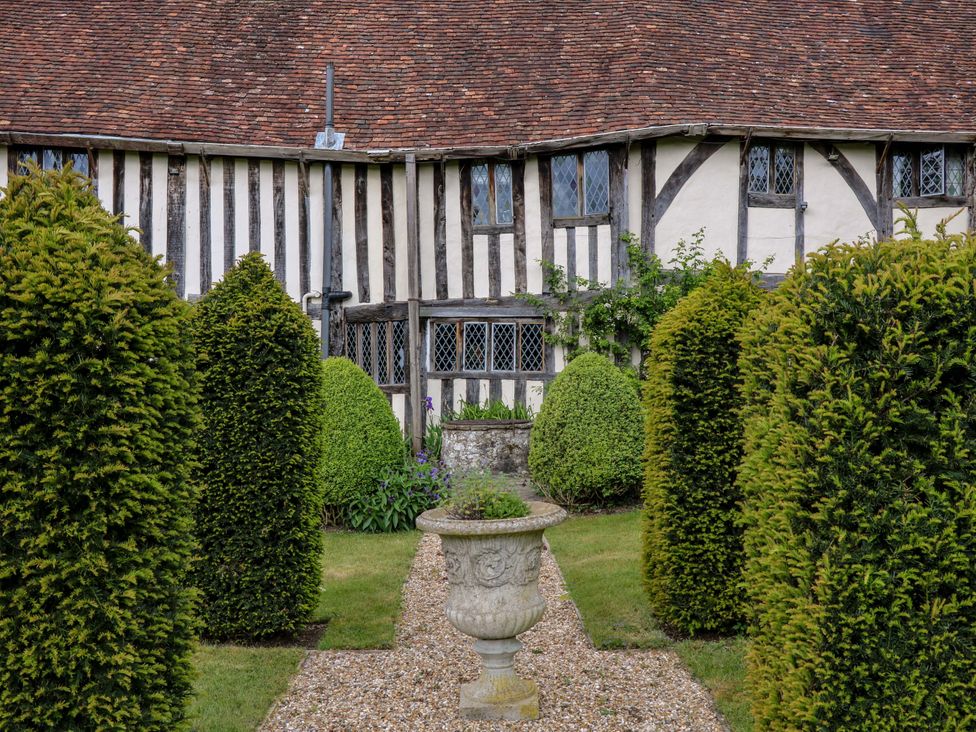 A garden with hedges and a stone urn at Dukes Place in 