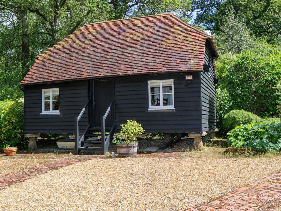 A cottage with stairs and windows surrounded by greenery at The Granary in Petworth