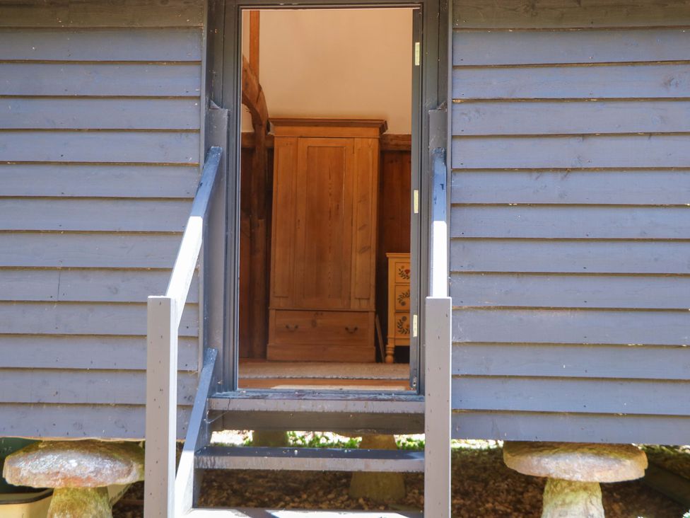 A view of the entrance with steps and wooden furniture at The Granary in Petworth