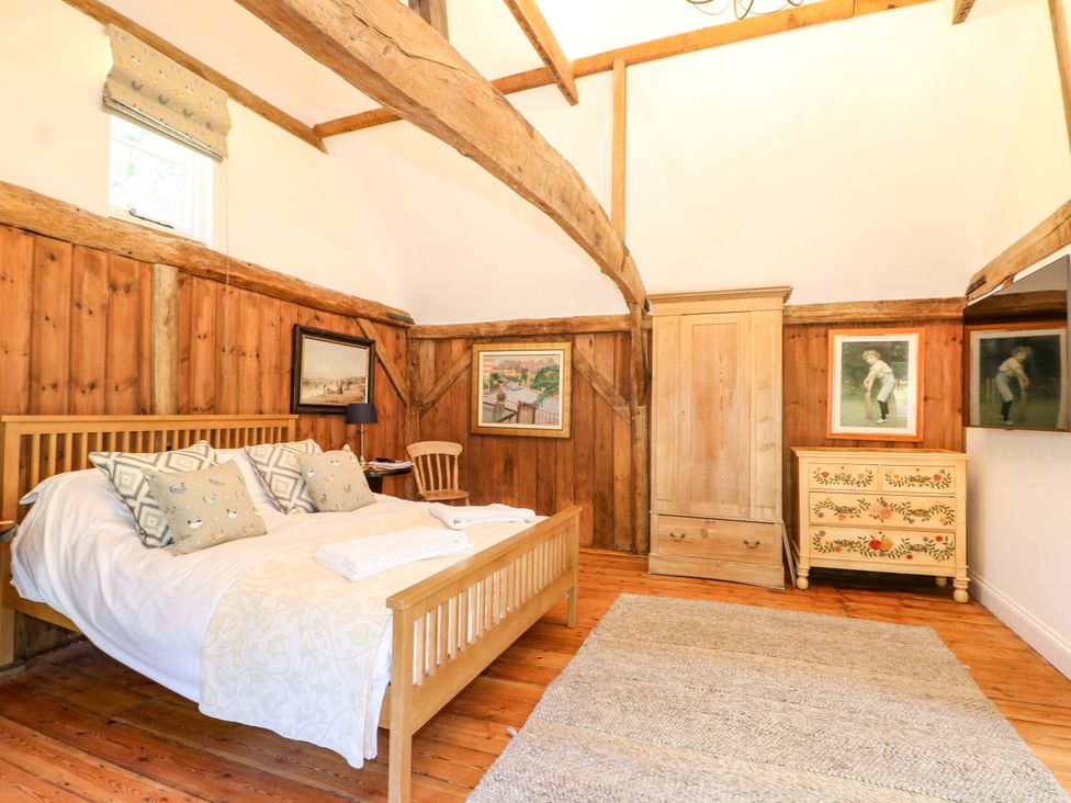 A bedroom with a bed and wooden furniture at The Granary in Petworth
