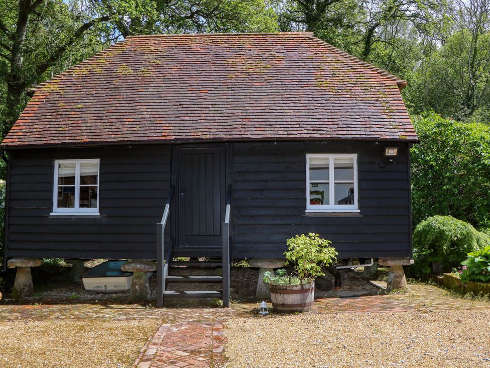 A black wooden building with a front door and windows at The Granary in Petworth