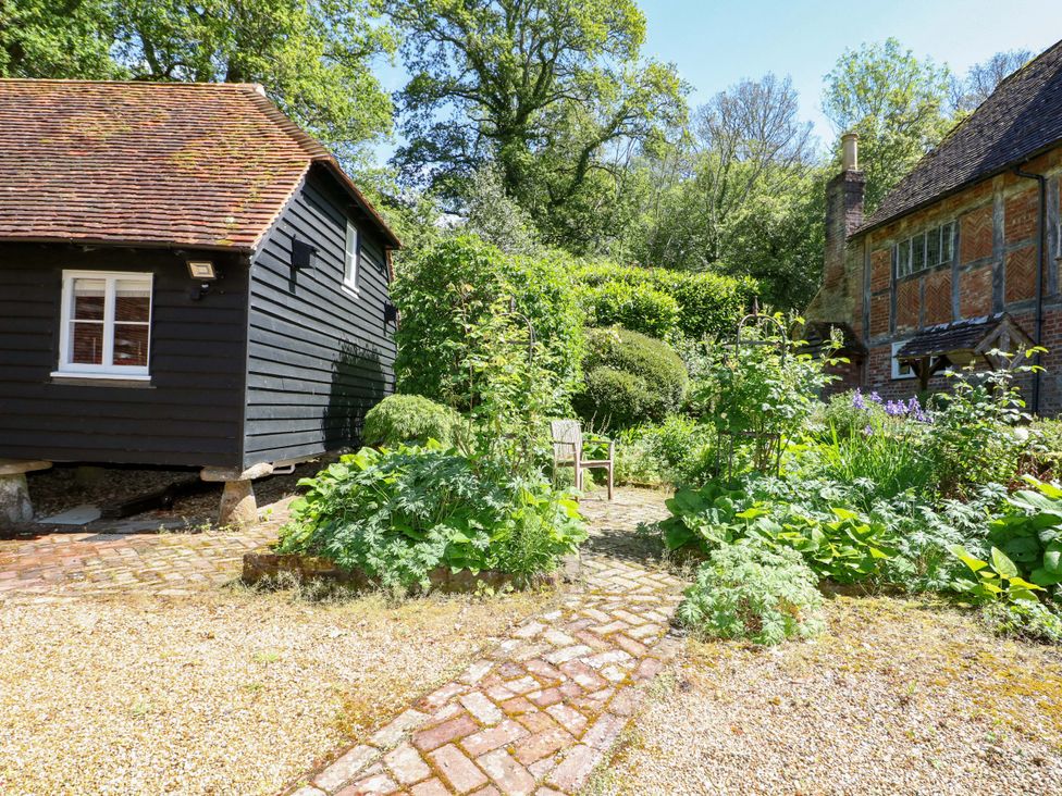 A garden with a pathway, small chair, and shed at The Granary in Petworth
