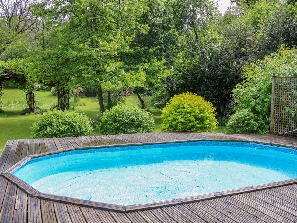 A swimming pool surrounded by decking and greenery at The Granary in Petworth