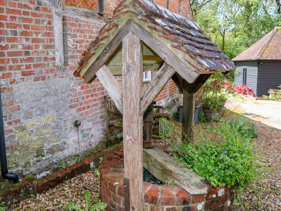 A wooden well structure with plants surrounding it at The Granary in Petworth