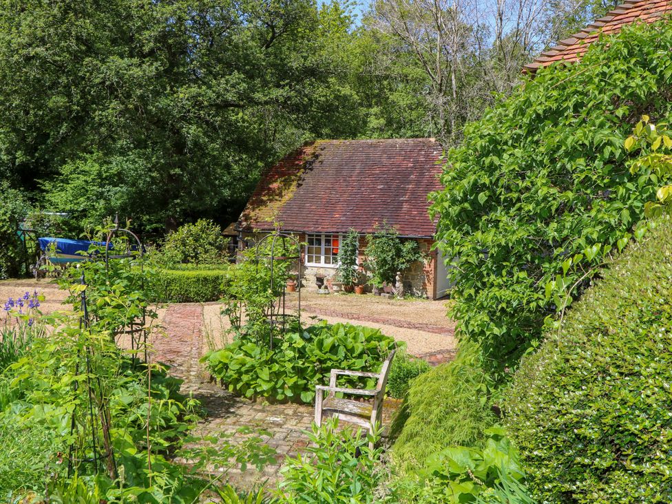 A garden with a house and gravel path at The Granary in Petworth