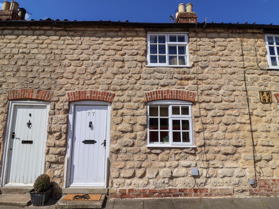 A stone cottage with white doors and windows at The Cook’s Cottage in Malton