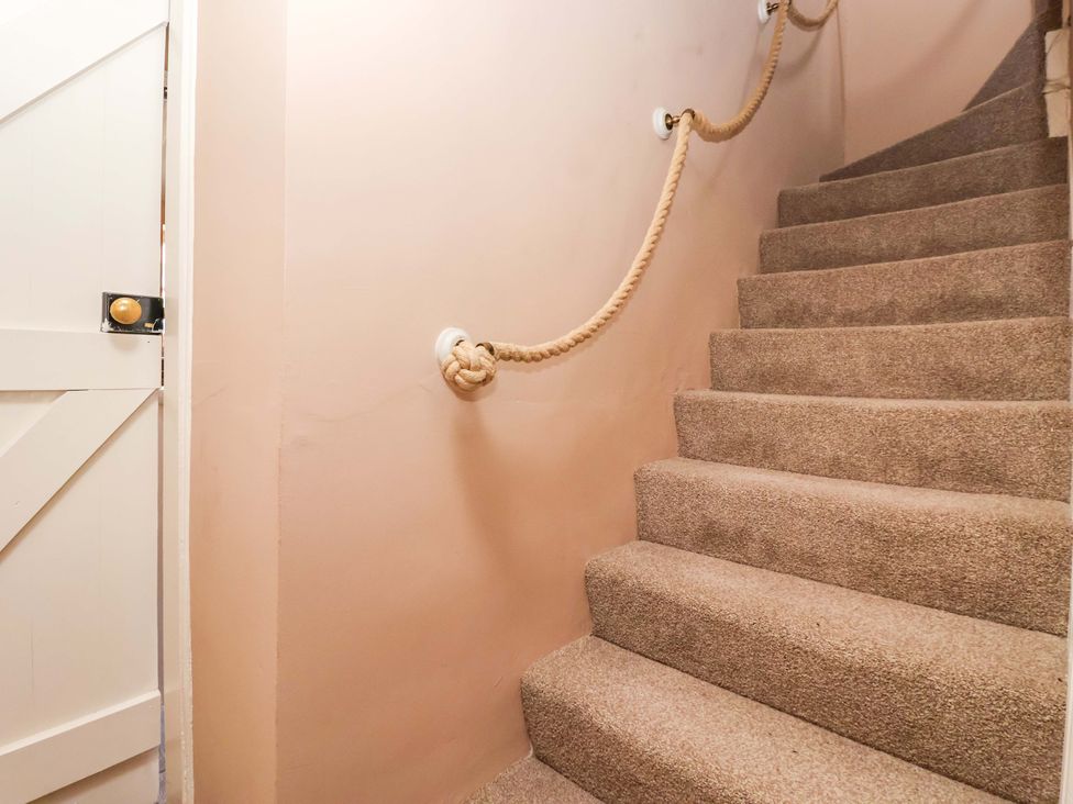A staircase with carpet and a rope handrail at The Cook’s Cottage in Malton