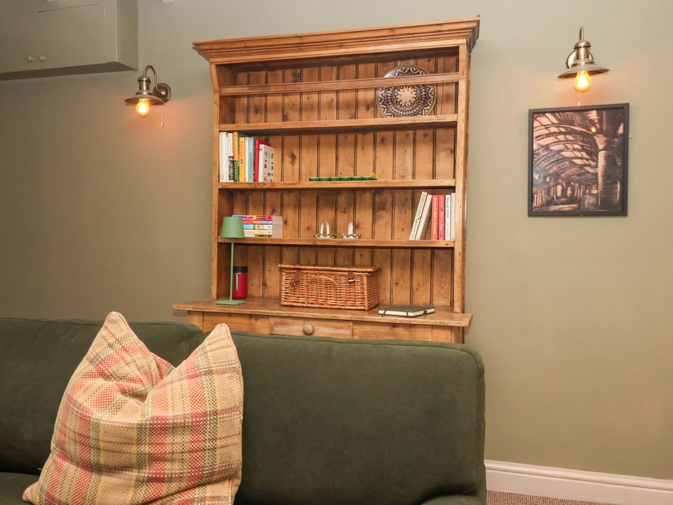 A snug with a wooden shelf and books at The Cook’s Cottage in Malton