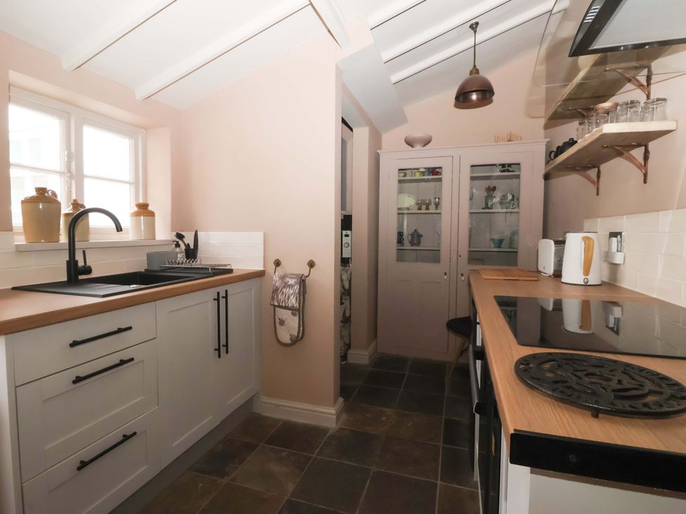 A kitchen with a sink and cabinets at The Cook’s Cottage in Malton