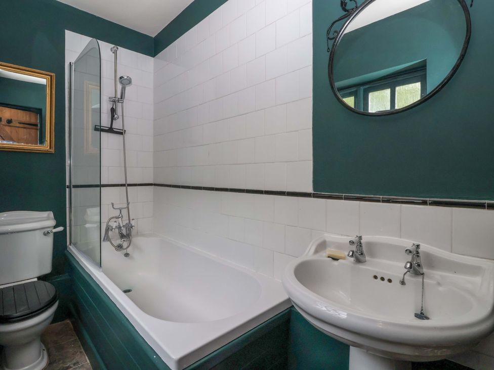 A bathroom with a bathtub, shower, toilet, and sink at The Cook’s Cottage in Malton