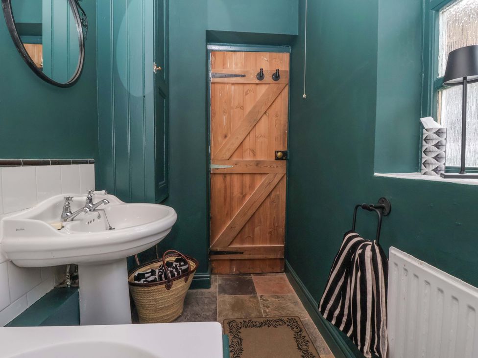 A bathroom with a sink and wooden door at The Cook’s Cottage in Malton