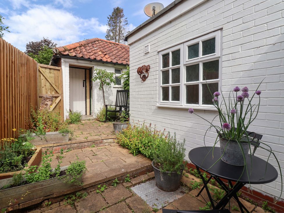 A garden area with paved pathway and plants at The Cook’s Cottage in Malton