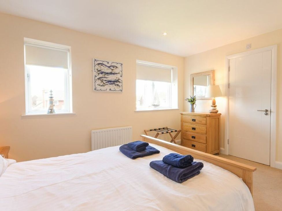 A bedroom with a bed and wooden furniture at Beach Walk in Chathill