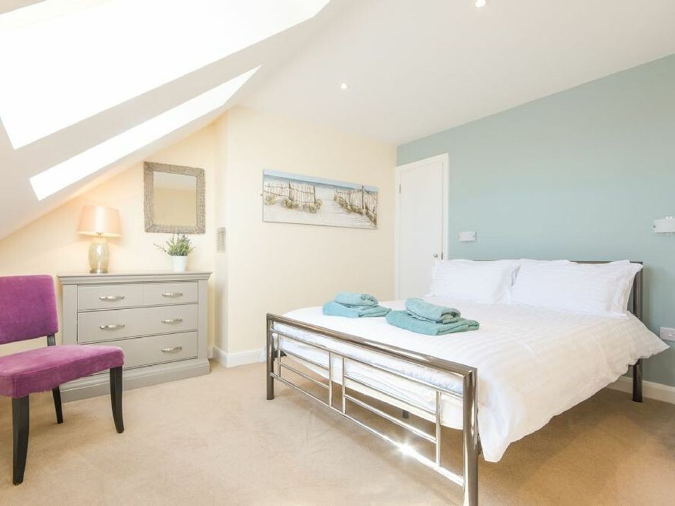 A bedroom with a bed, towels on the bed, and a chest of drawers at Beach Walk in Chathill