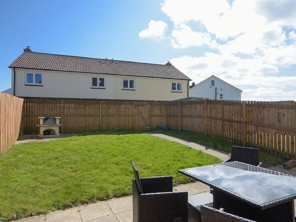 A garden with a table and chairs at Beach Walk in Chathill