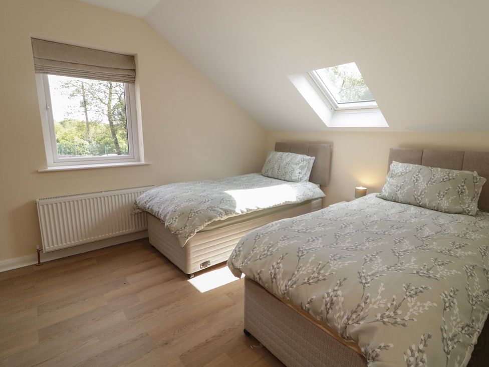 A bedroom with two beds and a window at Brook Cottage in Coleraine