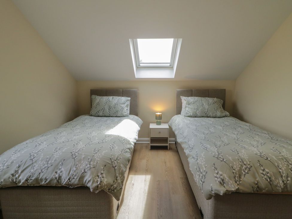 A bedroom with two beds and a bedside table at Brook Cottage in Coleraine