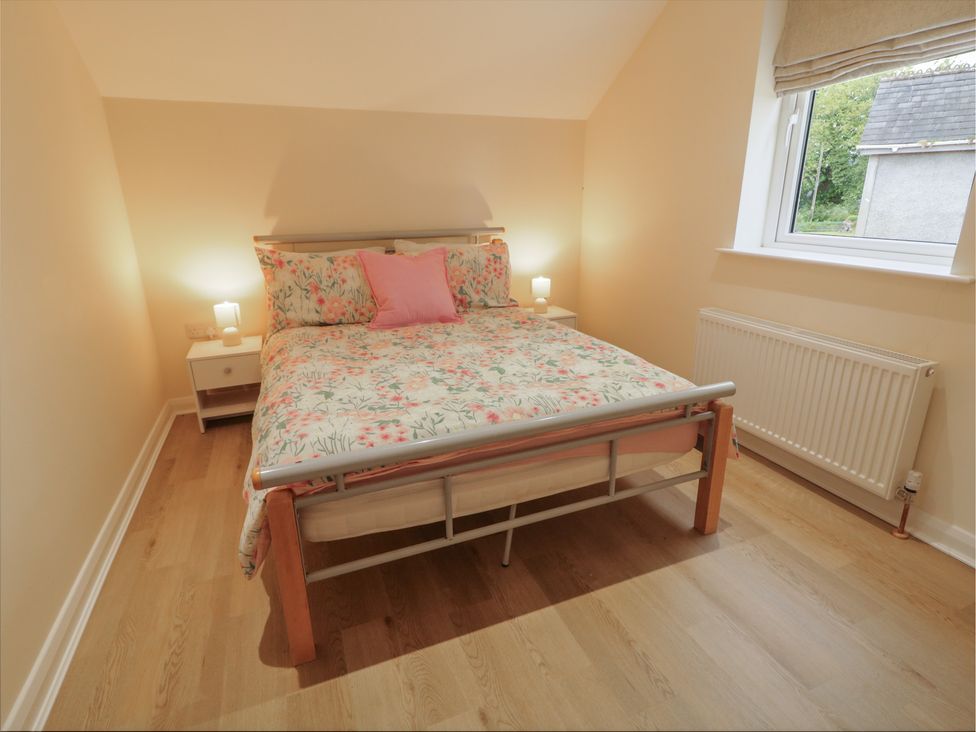A bedroom with a bed and nightstand at Brook Cottage in Coleraine