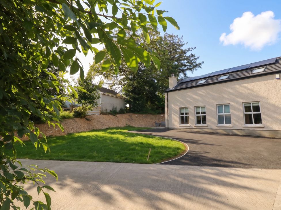A house with a grassy area and driveway at Brook Cottage in Moneydig near Coleraine