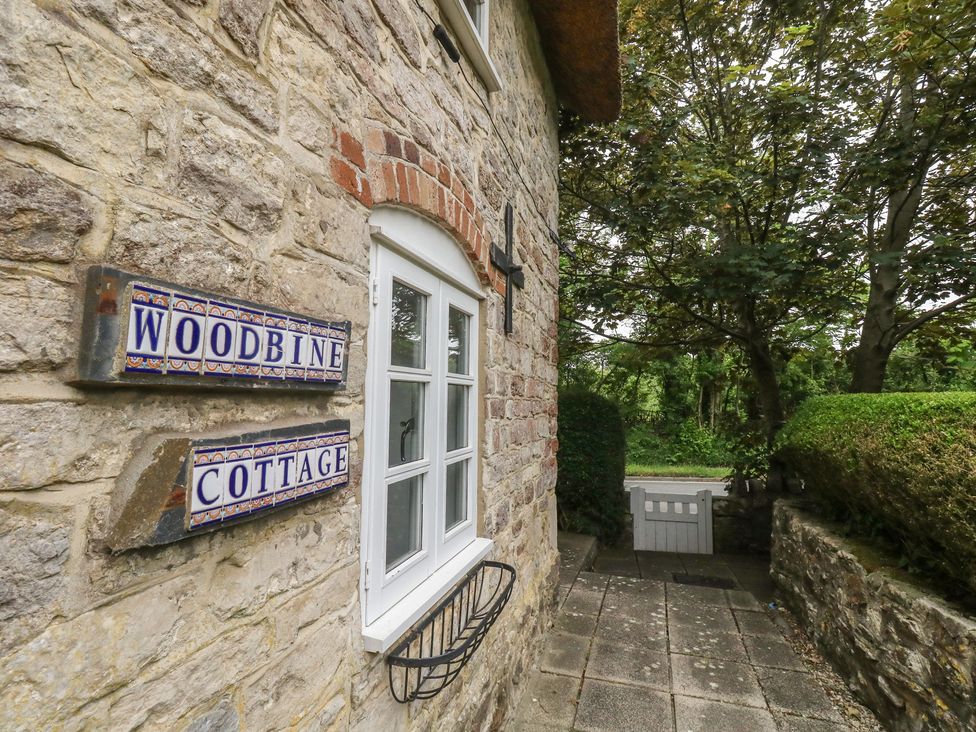 Exterior view of Woodbine Cottage with stone wall and pathway in Weymouth