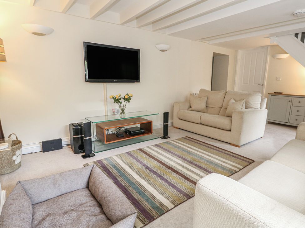 A living room with a television and sofa at Woodbine Cottage in Weymouth