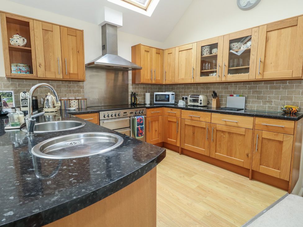 A kitchen with wooden cabinets and appliances at Woodbine Cottage in Weymouth
