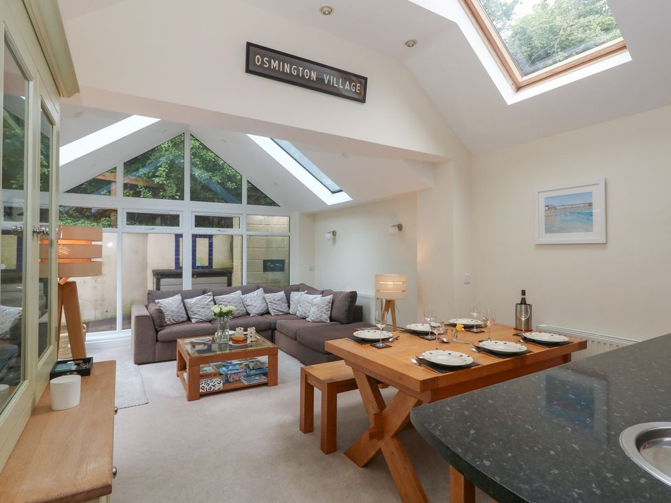 A living room with a sofa and dining table at Woodbine Cottage in Weymouth