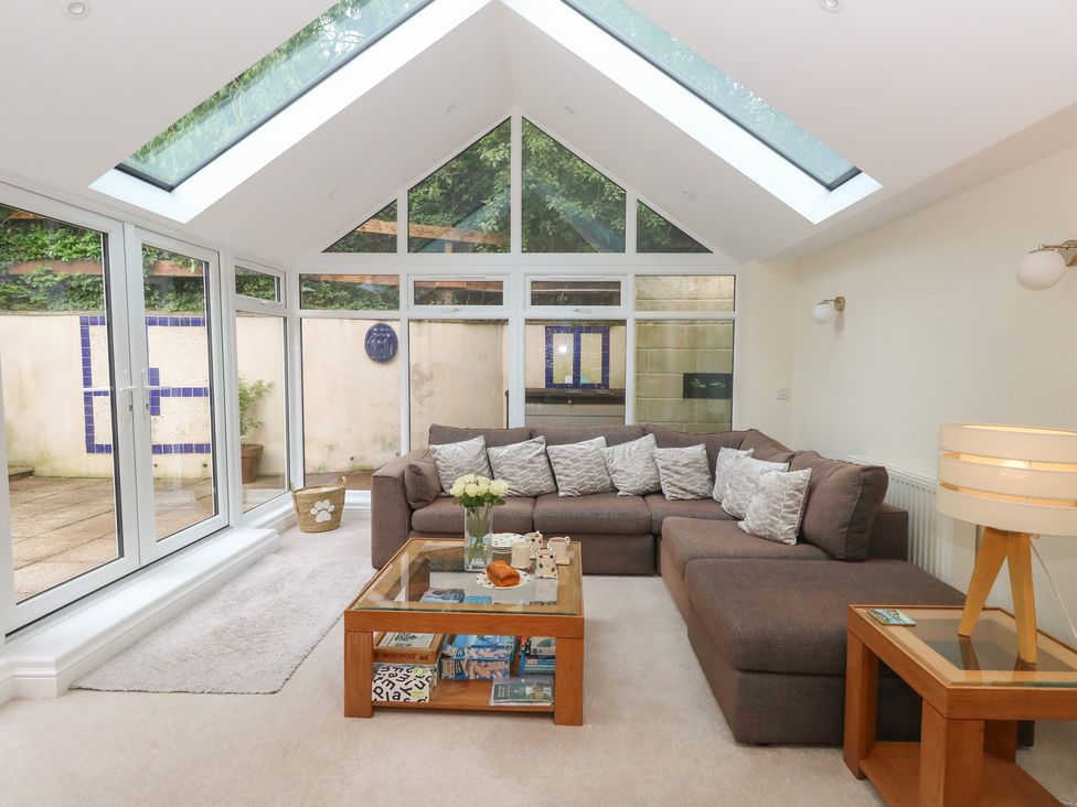A sunroom with a sofa and coffee table at Woodbine Cottage in Weymouth