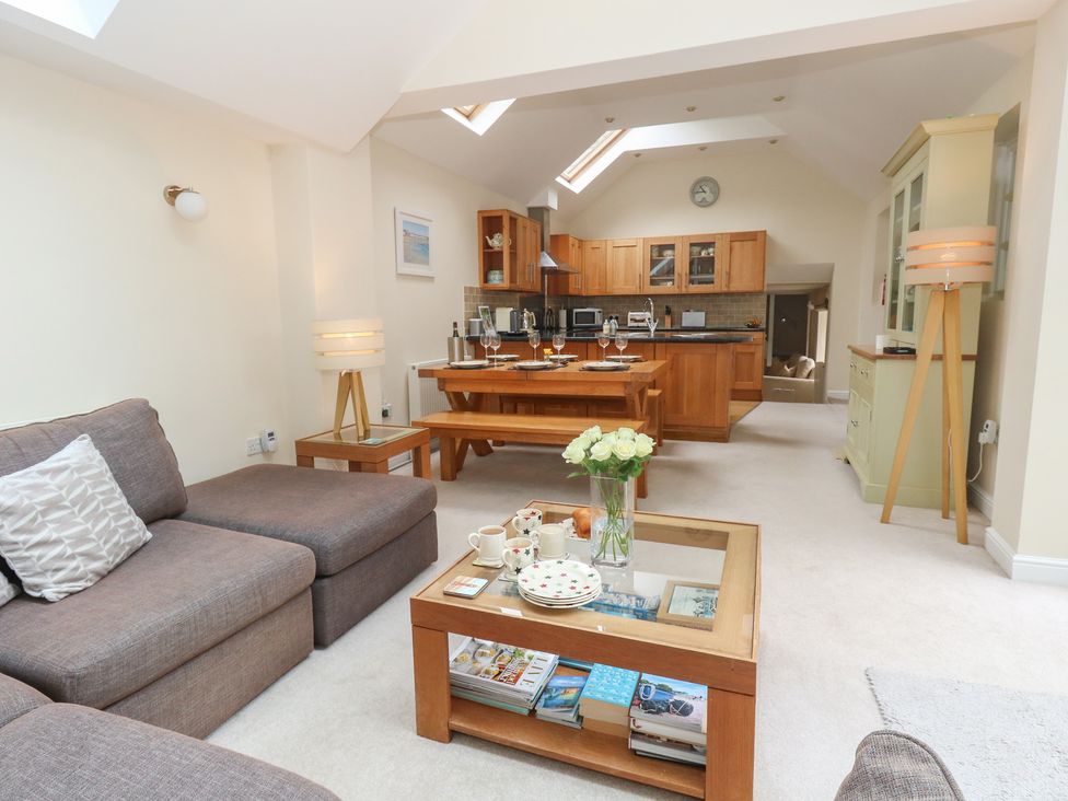 A living room with a kitchen and dining table at Woodbine Cottage in Weymouth