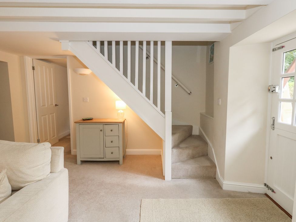 A hallway with stairs and a console table at Woodbine Cottage in Weymouth