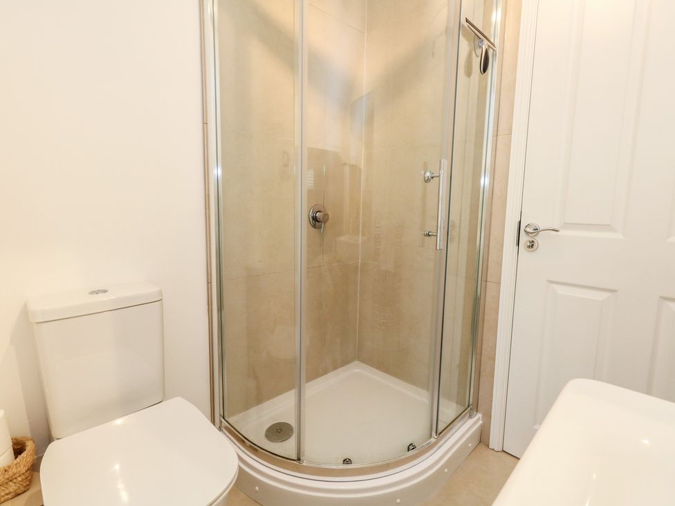 A bathroom with a shower and a toilet at Woodbine Cottage in Weymouth