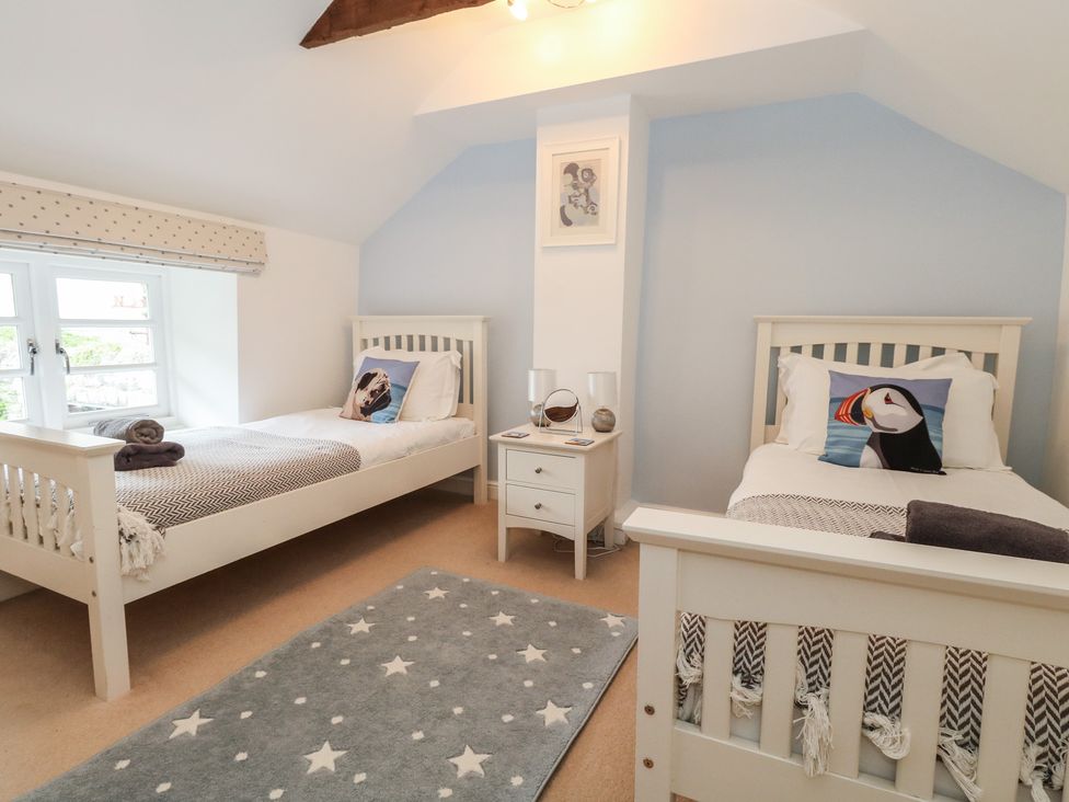 A bedroom with two beds and a nightstand at Woodbine Cottage in Weymouth