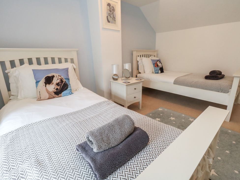 A bedroom with two single beds and a bedside table at Woodbine Cottage in Weymouth