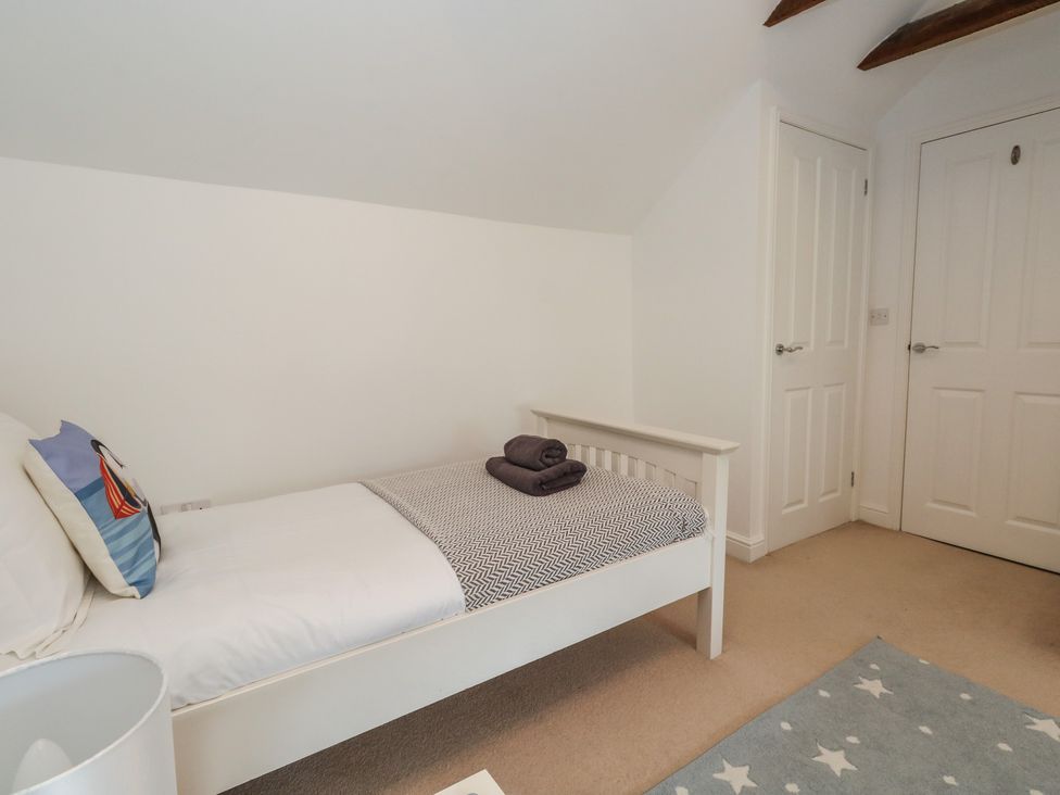 A bedroom with a bed and two doors at Woodbine Cottage Weymouth