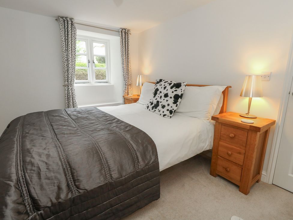 A bedroom with a bed and nightstand at Woodbine Cottage in Weymouth