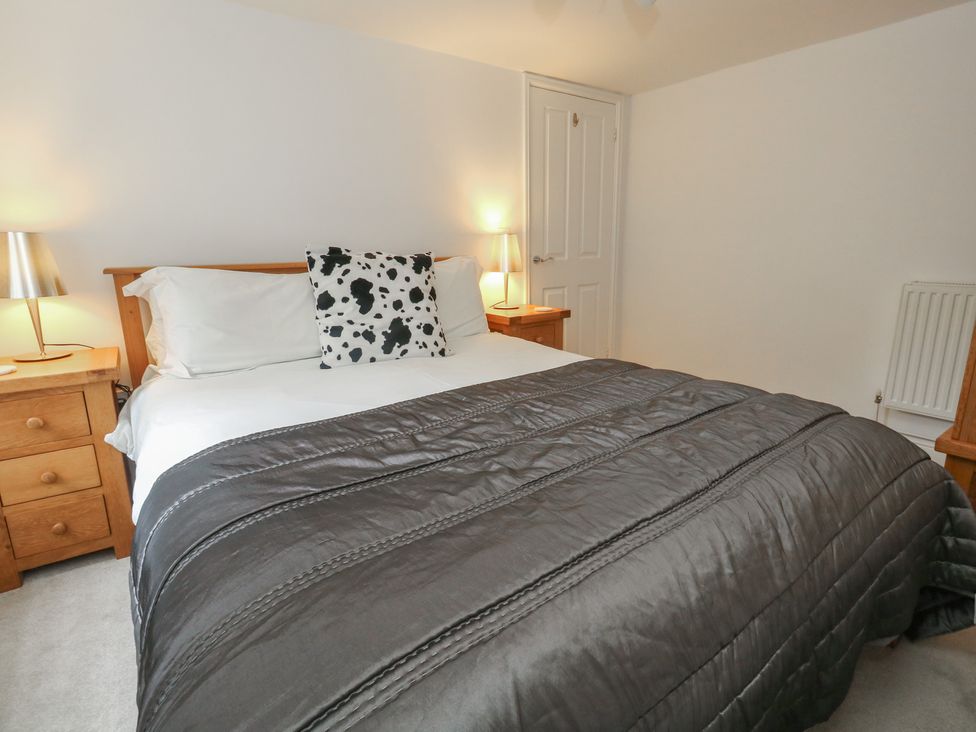 A bedroom with a bed and nightstands at Woodbine Cottage in Weymouth