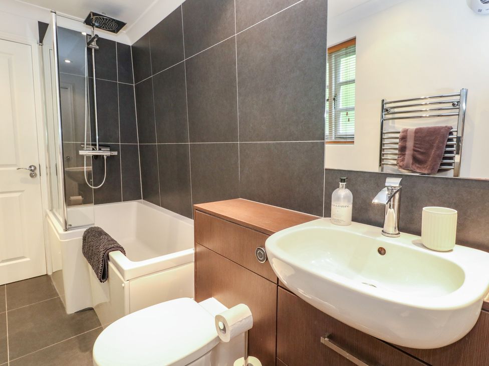 A bathroom with a shower and bathtub at Woodbine Cottage Weymouth