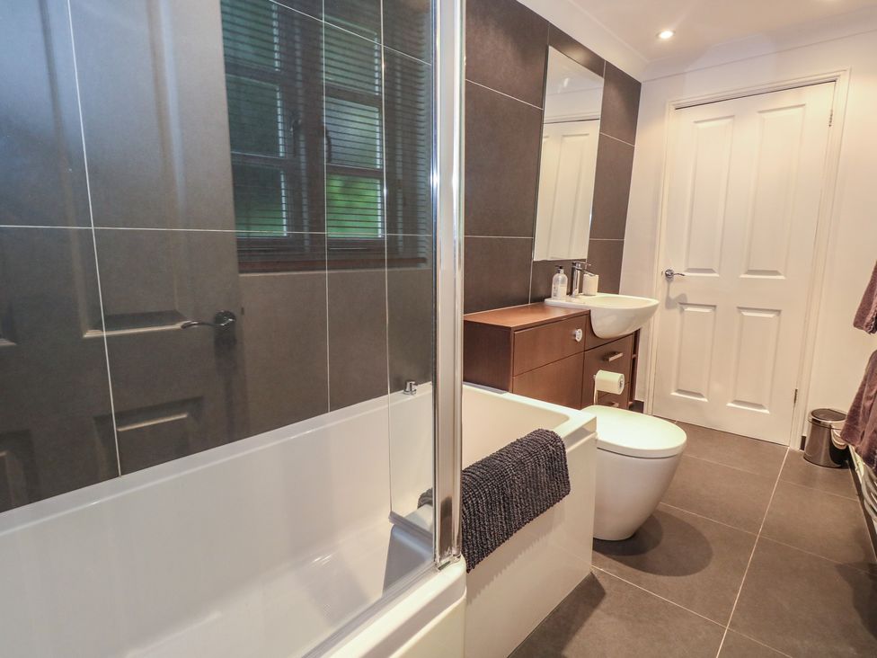 A bathroom with a bathtub and sink at Woodbine Cottage in Weymouth
