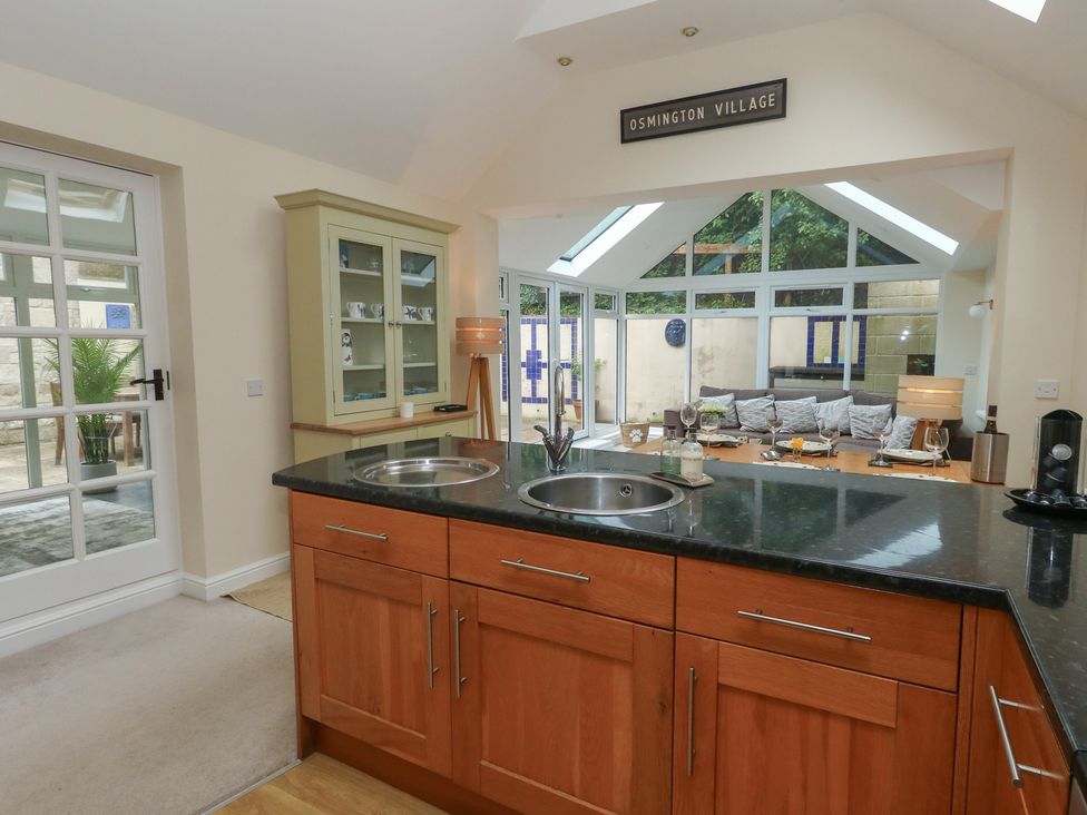 A kitchen with an island and glass doors at Woodbine Cottage in Weymouth