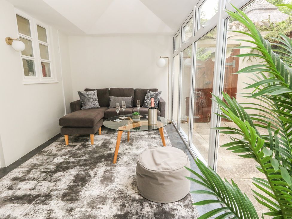 A conservatory with a sofa and a coffee table at Woodbine Cottage in Weymouth