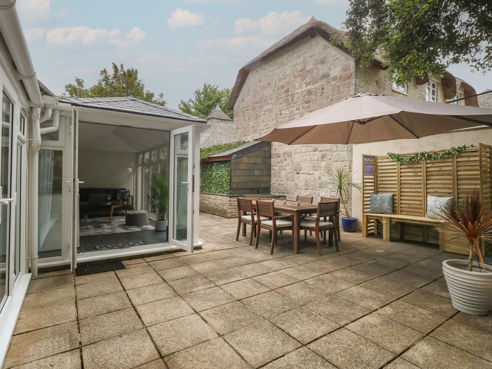 A garden with a dining area and seating at Woodbine Cottage in Weymouth