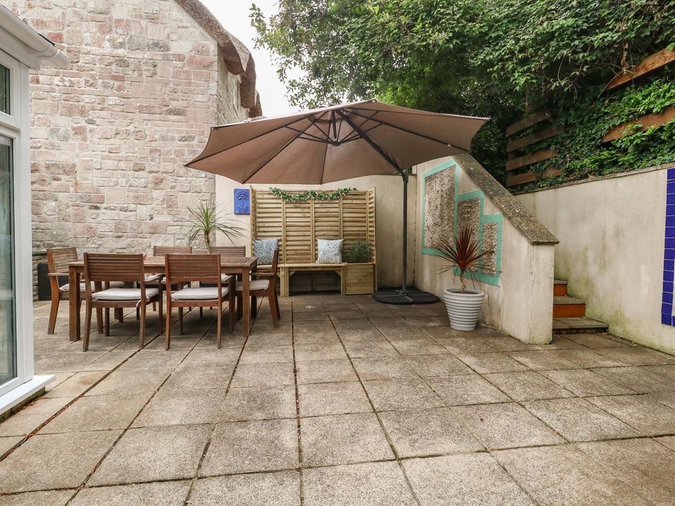 A garden with a table and chairs under an umbrella at Woodbine Cottage in Weymouth
