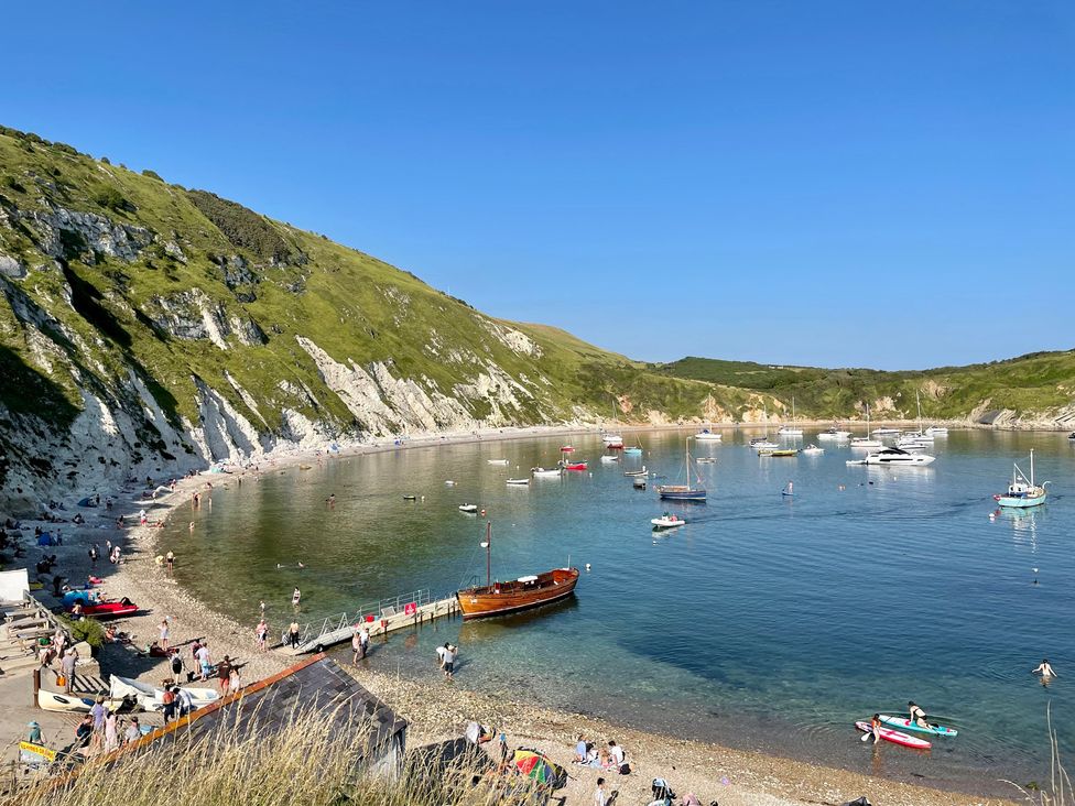 A beach with boats and people at Woodbine Cottage in Osmington